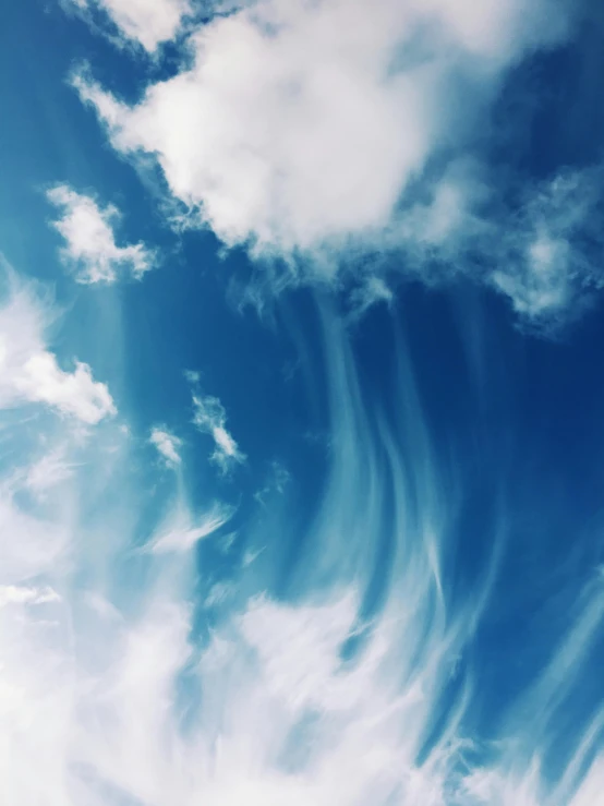 a plane flying through a cloudy blue sky, an album cover, unsplash, aestheticism, harmony of swirly clouds, profile picture, alcohol with blue delirium skies, vertical wallpaper