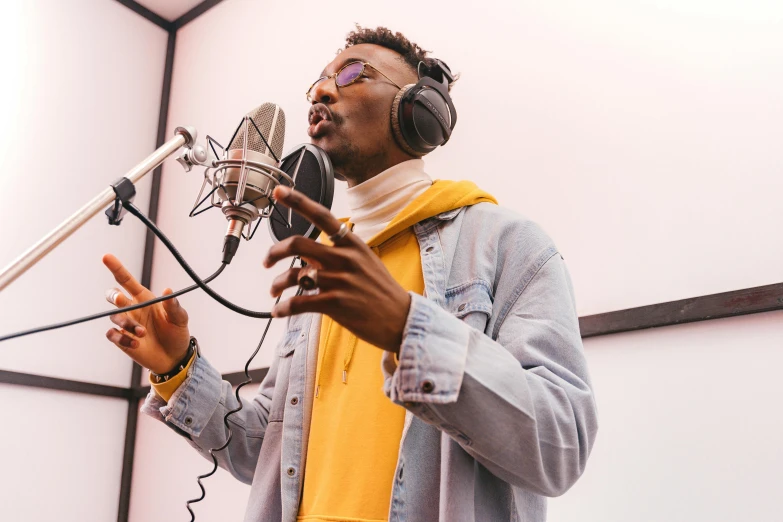 a man with headphones standing in front of a microphone, trending on pexels, adut akech, taking from above, practice, backup vocalists