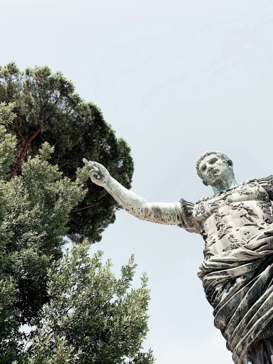a statue of a man standing next to a tree, inspired by Augustus Dunbier, pexels contest winner, colosseo, raising an arm, 🚿🗝📝, profile image