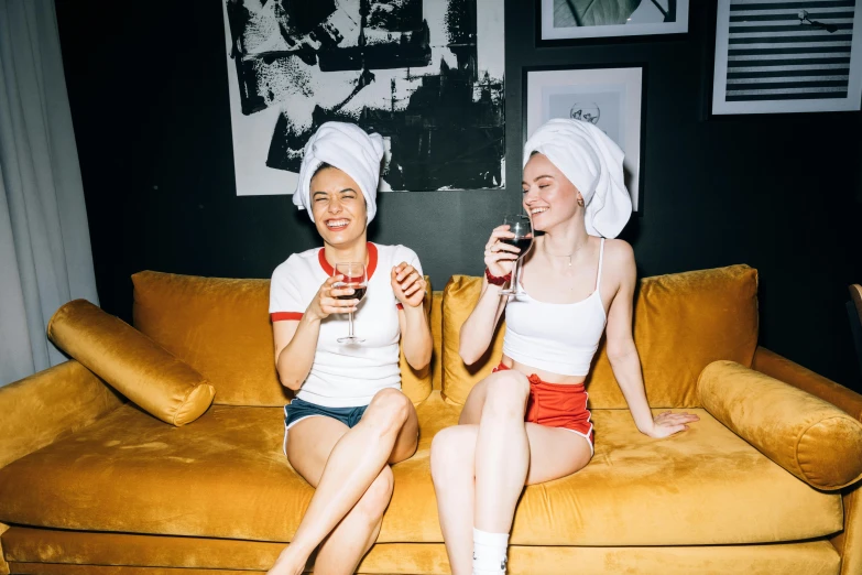 a couple of women sitting on top of a couch, by Julia Pishtar, pexels contest winner, wearing a white bathing cap, themed after wine, nightlife, hana alisa omer