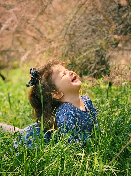 a little girl laying on top of a lush green field, pexels contest winner, symbolism, laughing hysterically, profile image, spring early, high quality screenshot