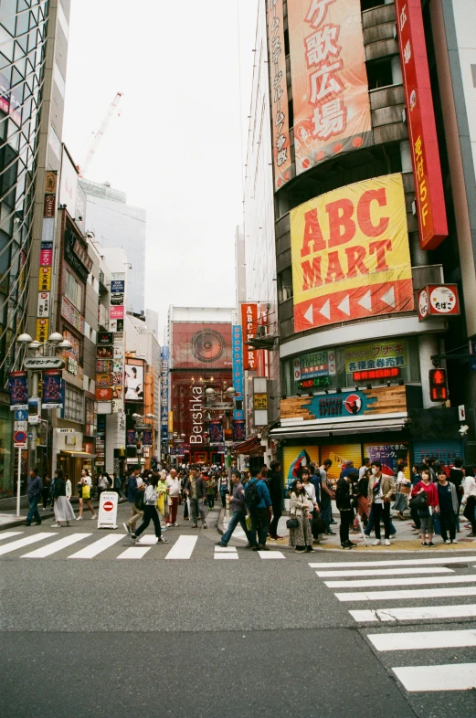 a group of people crossing a street in a city, inspired by Kanō Hōgai, international typographic style, lots of signs and shops, photograph of the city street, taken in the 2000s, square