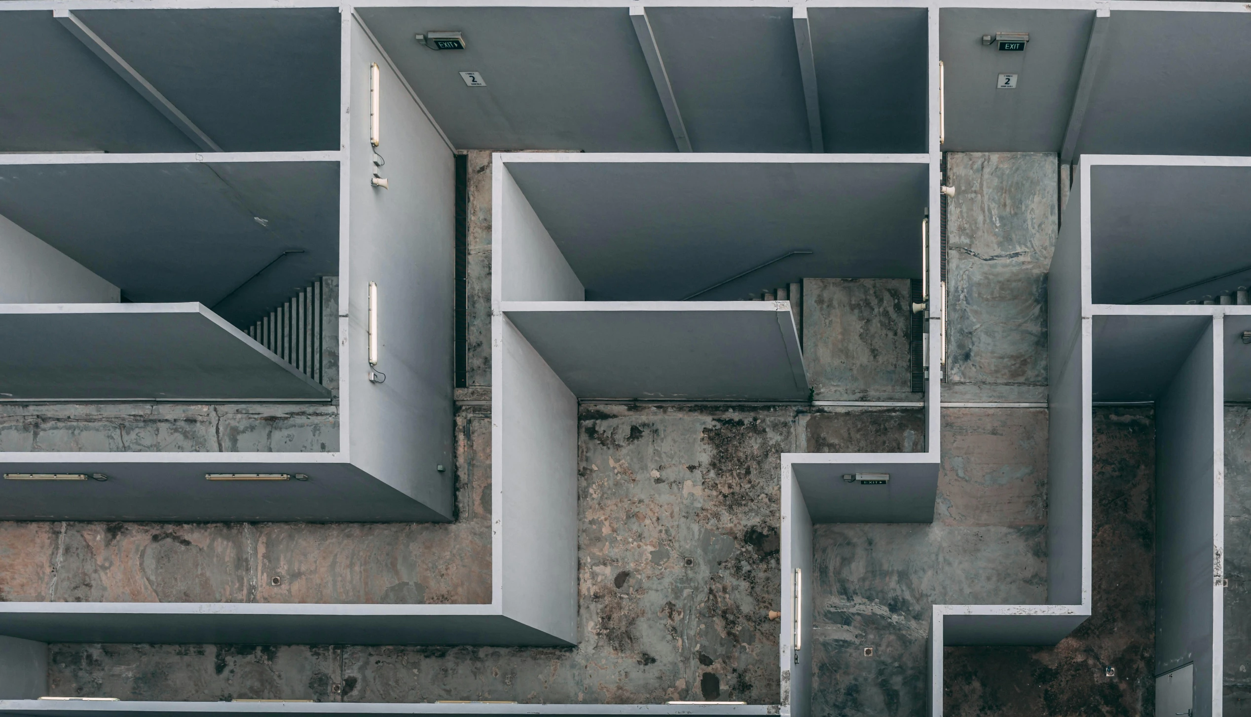 an aerial view of a building with multiple balconies, inspired by Donald Judd, pexels contest winner, brutalism, broken down grey wall, abstract conceptual, picture of an interior loft, maze