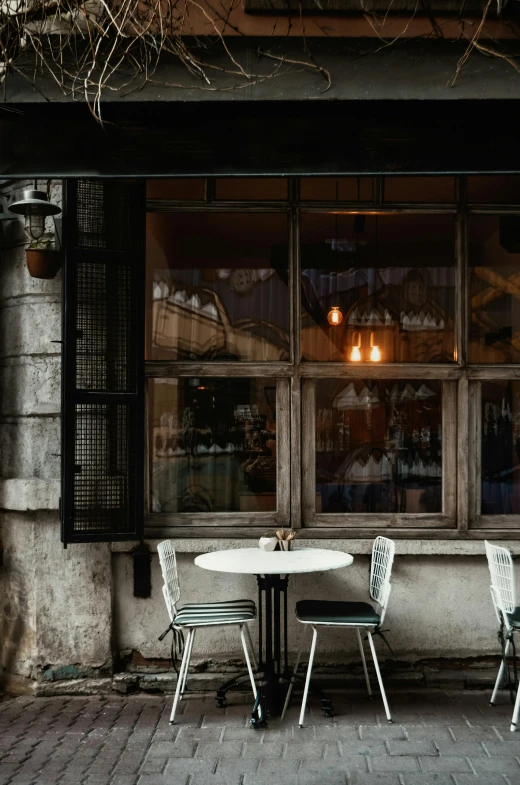 a couple of tables that are outside of a building, pexels contest winner, moody neutral hipster tones, bars on the windows, old world, mixed materials