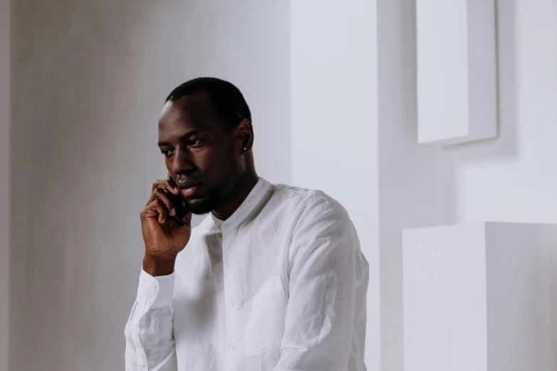 a man in a white shirt talking on a cell phone, pexels contest winner, les nabis, adut akech, thoughtful ), plain background, kano)