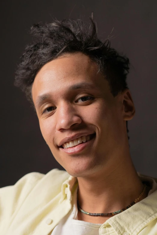 a close up of a person holding a cell phone, an album cover, inspired by Carlos Berlanga, featured on reddit, renaissance, smiling and looking directly, mixed race, shaven face, nonbinary model