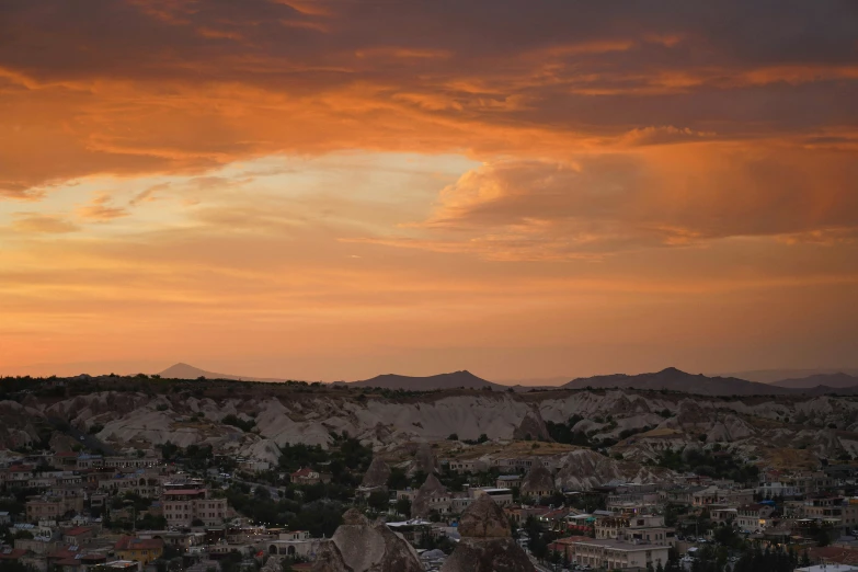 a view of a city from the top of a hill, pexels contest winner, romanticism, turkey, sunset with cloudy skies, badlands, brown