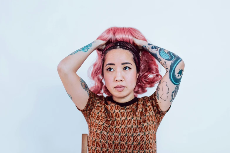 a woman with pink hair sitting in a chair, trending on pexels, realism, half asian, shrugging arms, photograph of a sleeve tattoo, bedhead