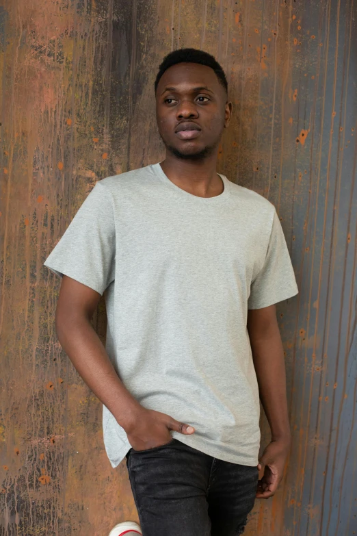 a young man standing in front of a rusty wall, a picture, inspired by Jesper Knudsen, plain white tshirt, in gunmetal grey, various sizes, rosen zulu