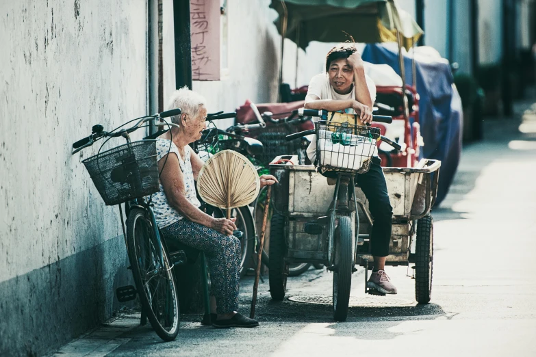a woman sitting next to a man on a bike, by Wen Zhenheng, pexels contest winner, old lady, avatar image, shady alleys, fan favorite