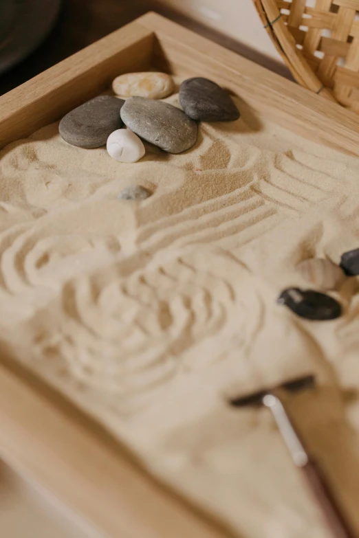 a wooden box sitting on top of a table filled with rocks, inspired by Gatōken Shunshi, unsplash, kinetic art, sand texture, close up to the screen, digging, calm face