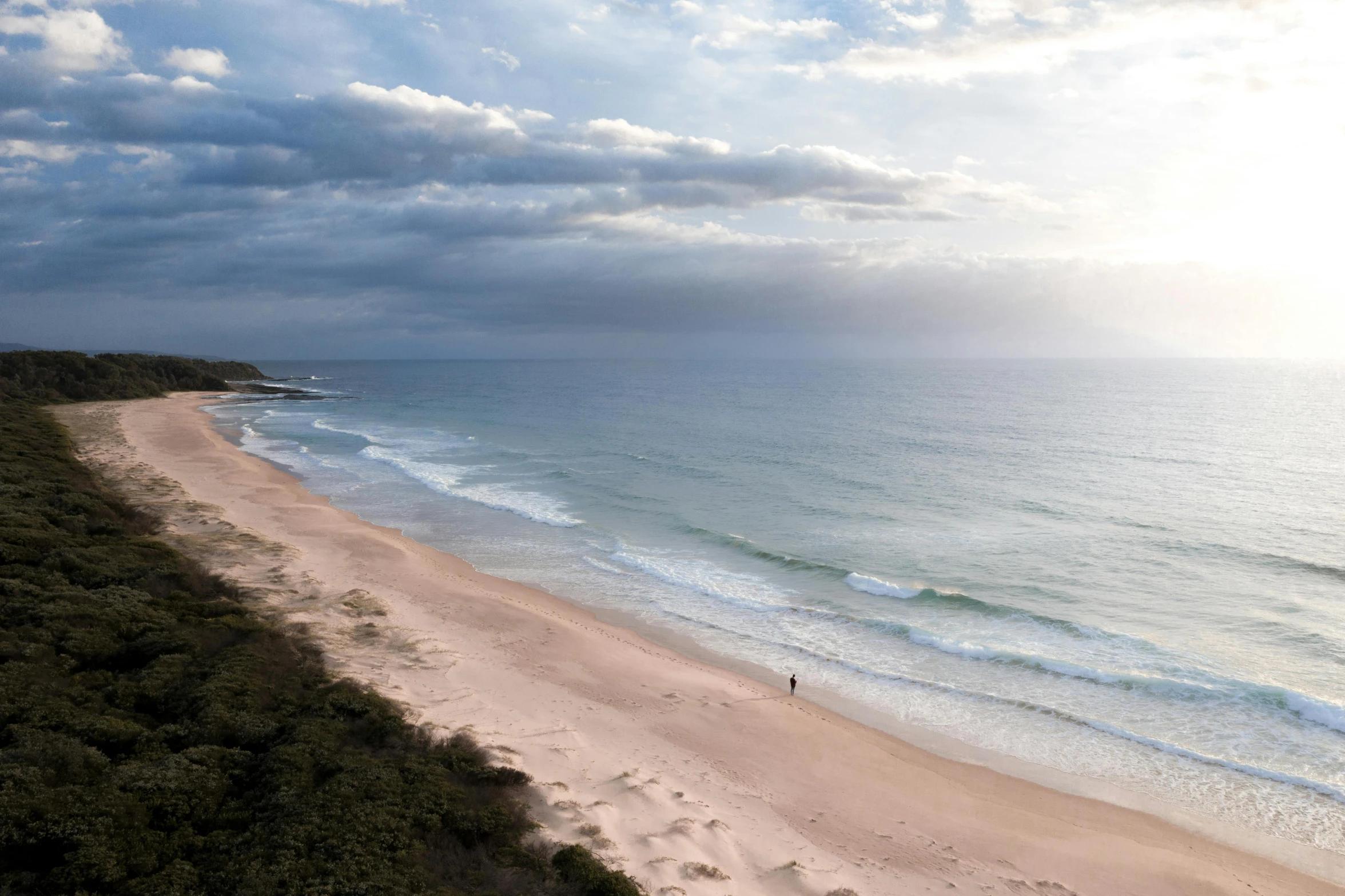 a man standing on top of a sandy beach next to the ocean, unsplash contest winner, australian tonalism, birdseye view, late morning, big sky, on the beach at noonday