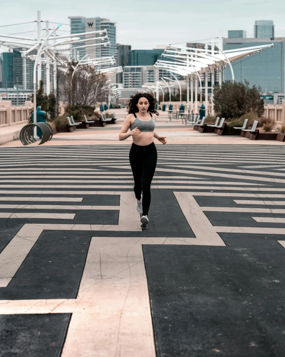 a woman running across a street with buildings in the background, a black and white photo, pexels contest winner, pixel art, wearing a cropped black tank top, maze like, amouranth, on a racetrack