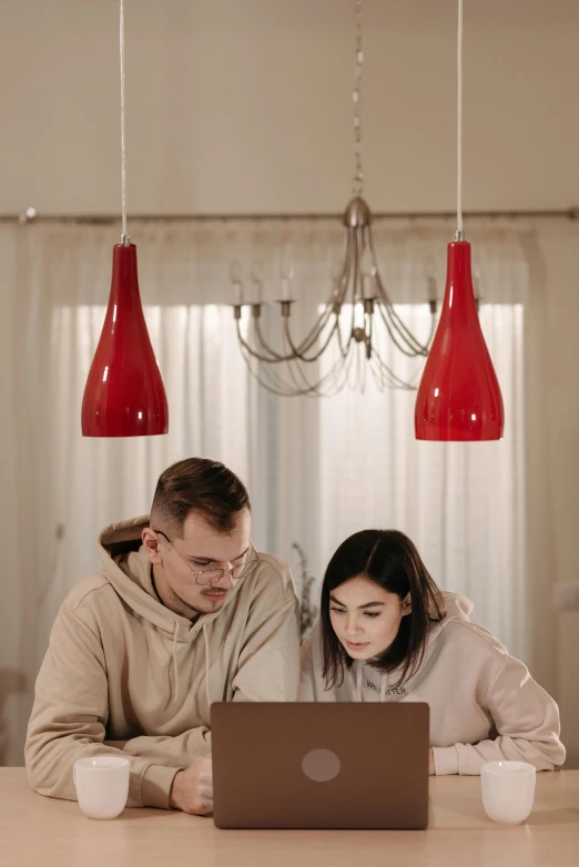 a man and a woman sitting at a table with a laptop, red and grey only, people looking at a house, bisexual lighting, high-quality photo
