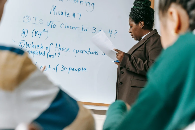 a woman standing in front of a whiteboard with writing on it, by Arabella Rankin, pexels contest winner, sitting in the classroom, a group of people, maths, photo of a black woman