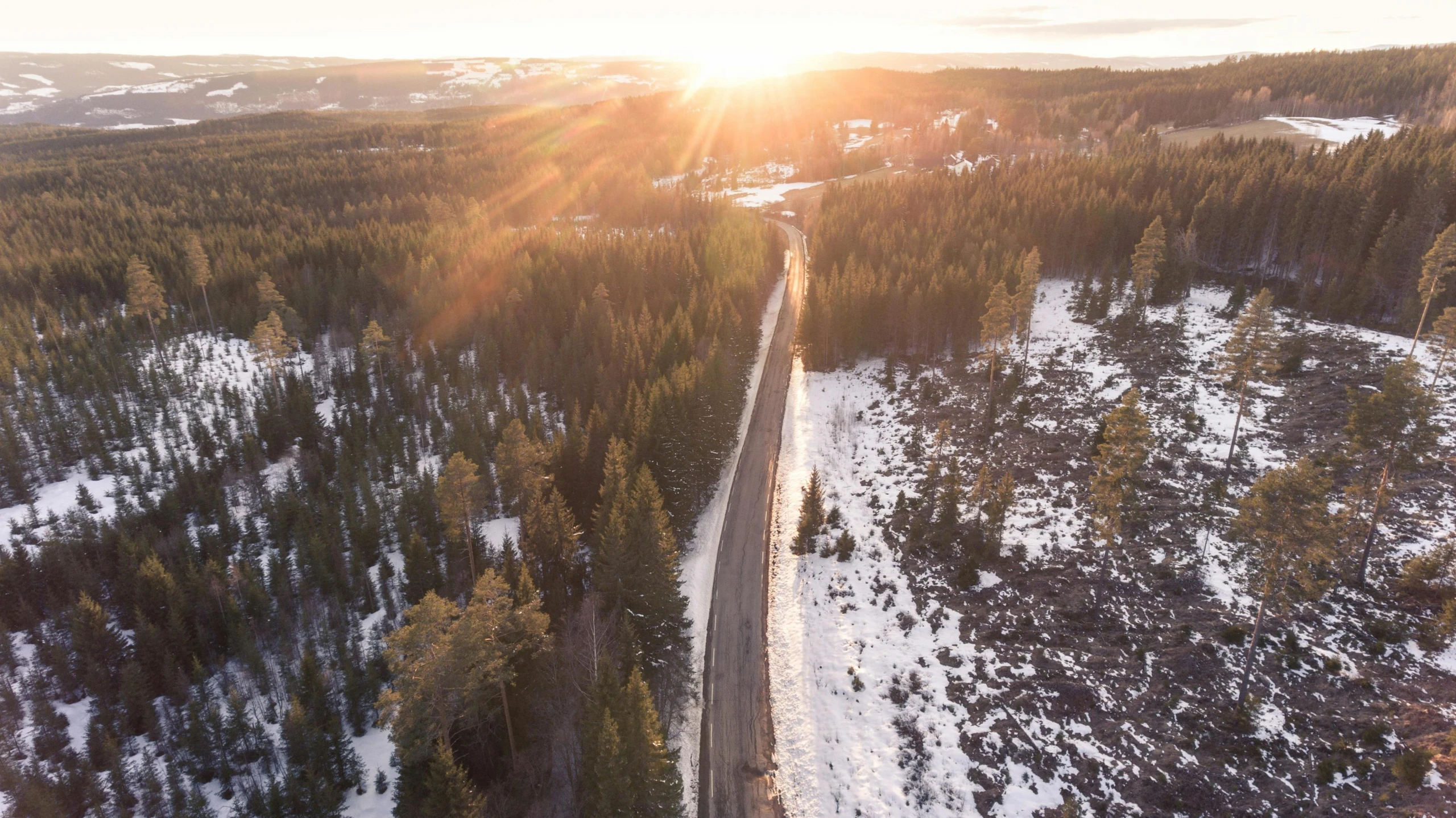 an aerial view of a road in the middle of a forest, by Veikko Törmänen, pexels contest winner, hurufiyya, sunset in a valley, sunny winter day, thumbnail, lit from the side