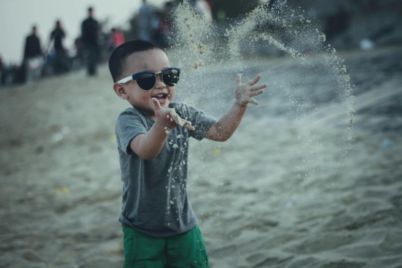 a little boy standing on top of a sandy beach, pexels contest winner, graffiti, wearing shades, flour dust flying, asian man, happy people