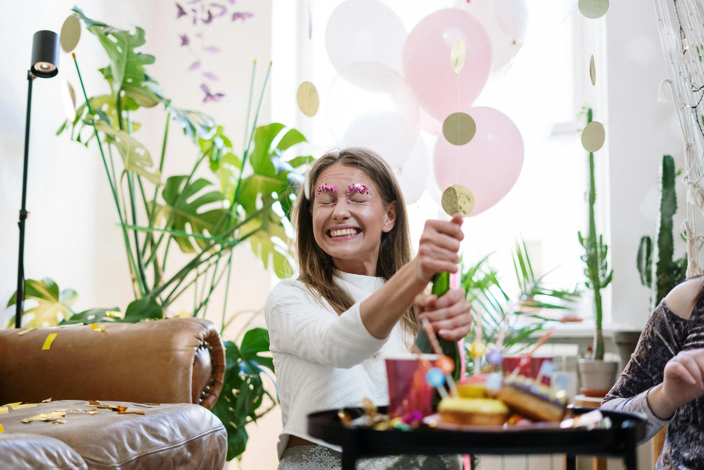 a group of people sitting around a table with balloons, woman with freckles, lighthearted celebration, profile image, decorations