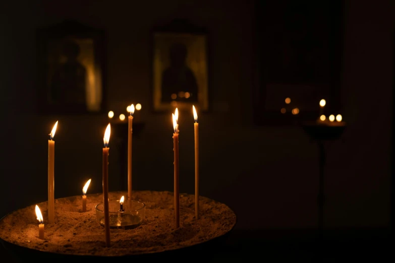 a group of lit candles sitting on top of a cake, pexels, baroque, in a monestry natural lighting, byzantine, standing in a dimly lit room, taken in the early 2020s