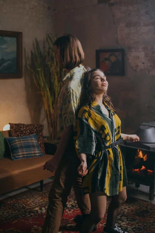 a woman standing next to a man in a living room, pexels contest winner, renaissance, yellow robe, wearing a flannel shirt, dancing around a fire, dreamy feeling