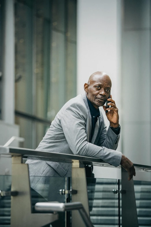 a man in a suit talking on a cell phone, by Andries Stock, pexels contest winner, samuel l jackson, atiba jefferson, grey skinned, professionally color graded
