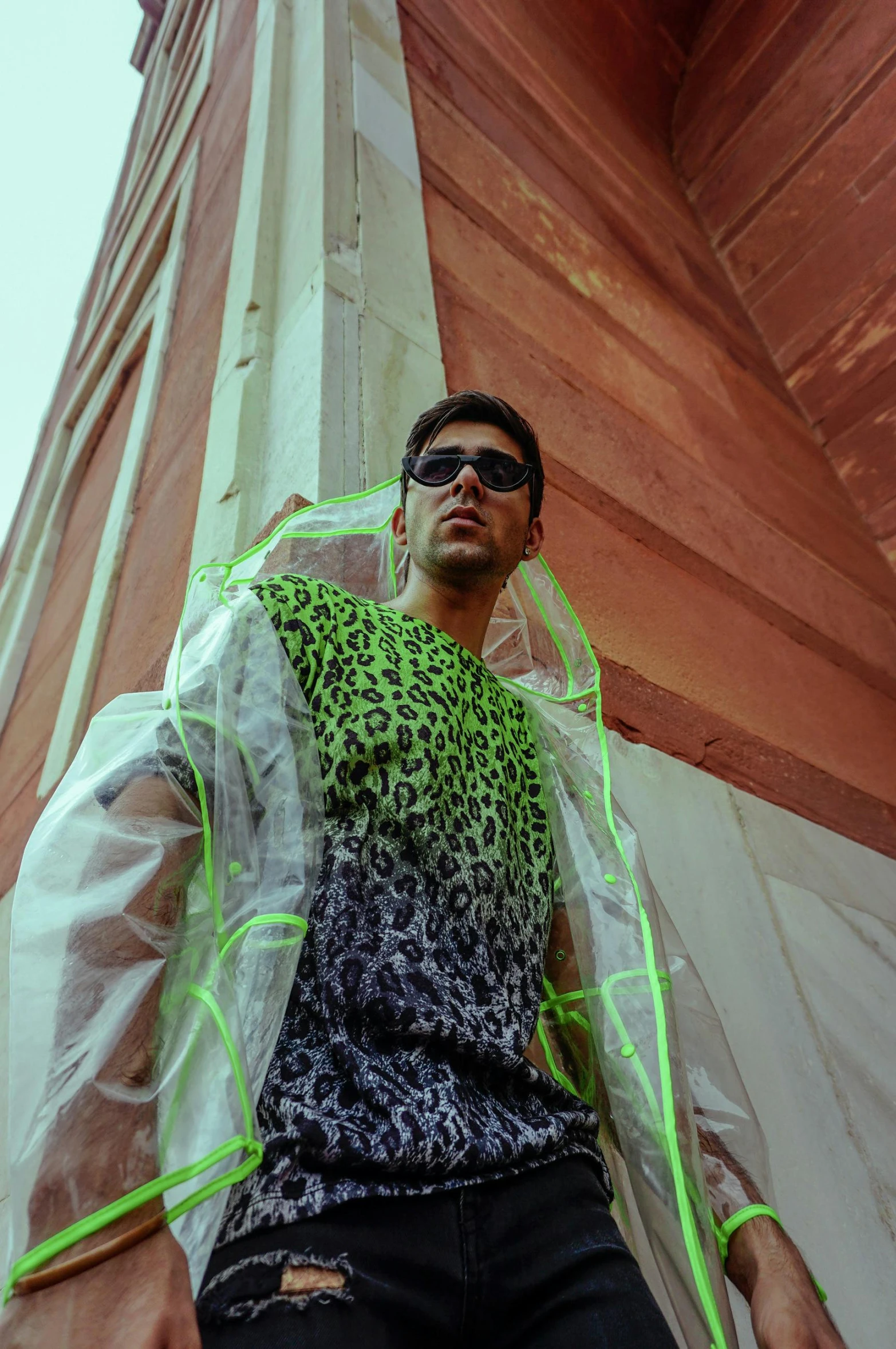 a man that is standing in front of a building, inspired by Ren Hang, renaissance, green cape, futuristic sunglasses, patterned clothing, covered in transparent cloth