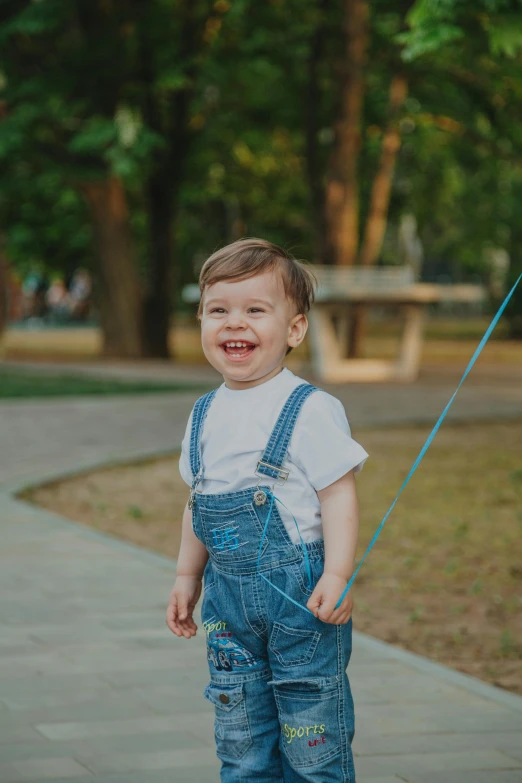 a little boy riding a skateboard down a sidewalk, a picture, pexels contest winner, blue overalls, smiling laughing, harnesses, walking at the park