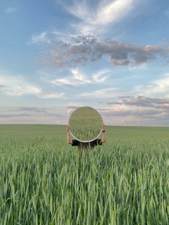 a person standing in a field holding a mirror, inspired by Scarlett Hooft Graafland, unsplash contest winner, surrealism, round-cropped, big sky, outside in a farm, profile image