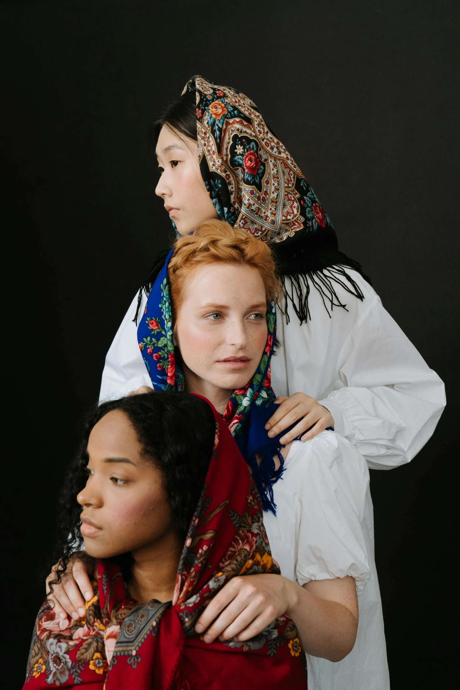 a couple of women standing next to each other, an album cover, inspired by Anna Füssli, trending on unsplash, renaissance, patterned scarf, mixed race, three women, russian clothes