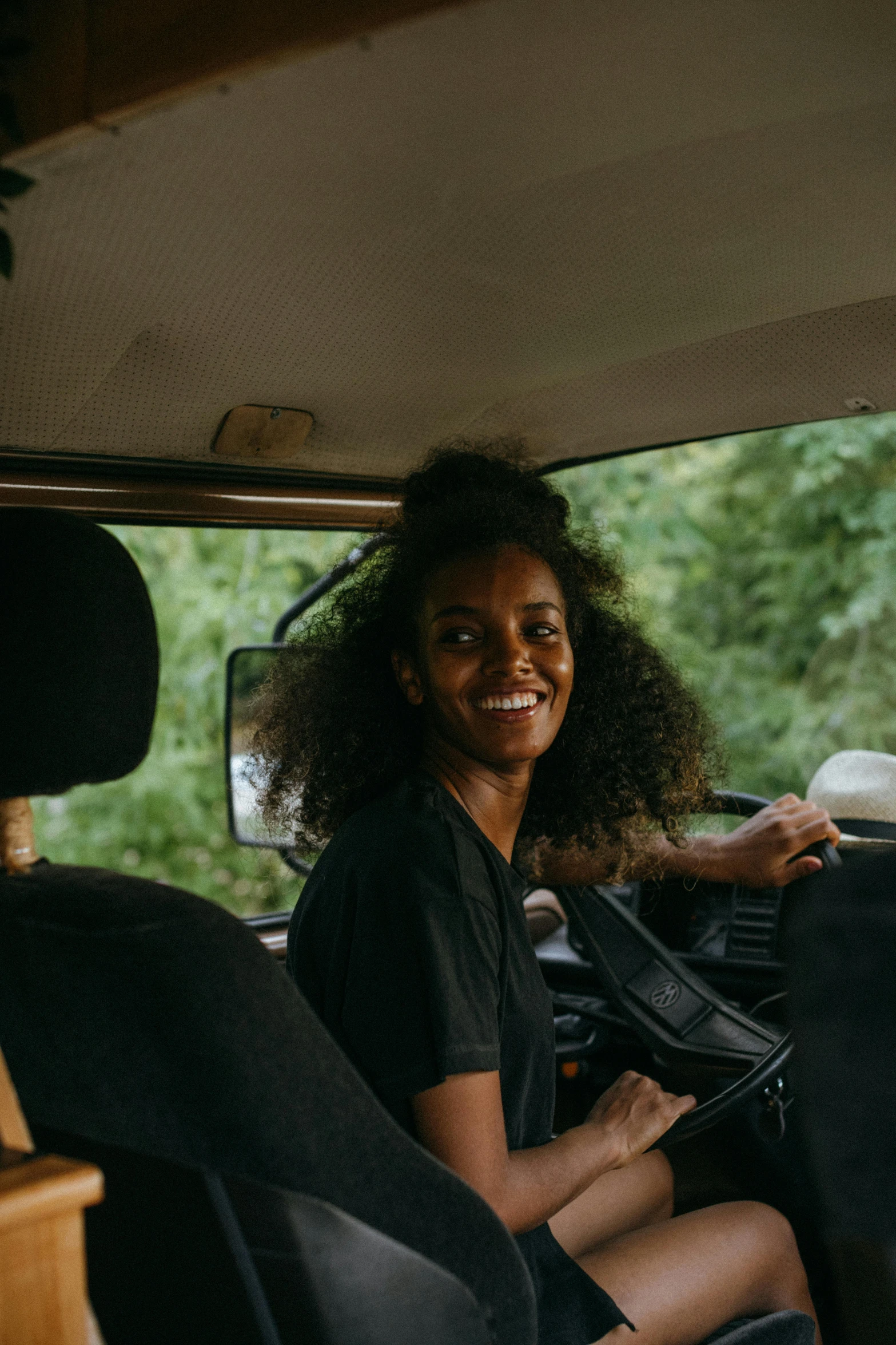 a woman sitting in the back seat of a van, pexels contest winner, happening, imaan hammam, welcoming grin, off-roading, black car