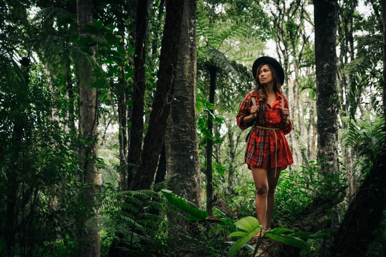 a woman standing in the middle of a forest, sumatraism, wearing a red plaid dress, tropical vibe, tamborine, wearing adventuring gear