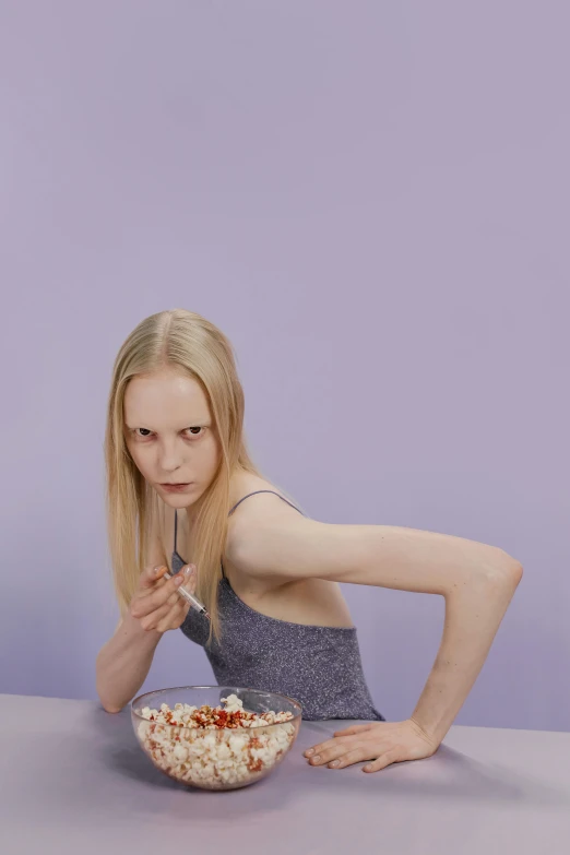 a woman sitting at a table with a bowl of food, an album cover, inspired by Vanessa Beecroft, trending on pexels, looking angry, lilac, anorexic figure, in a fighting pose