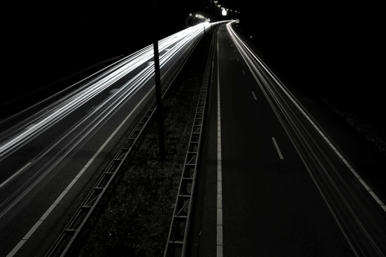 a black and white photo of a highway at night, by Adam Szentpétery, unsplash, realism, energy trails, hyperrealistic n- 4, car lights, taken in the late 2010s