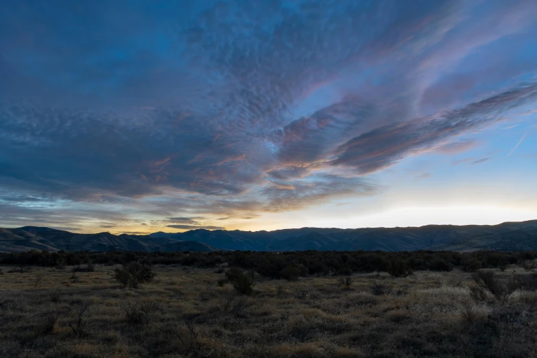 a field with some grass and mountains in the background, by Ryan Pancoast, unsplash, land art, twilight sky, panorama, central california, tectonic sky