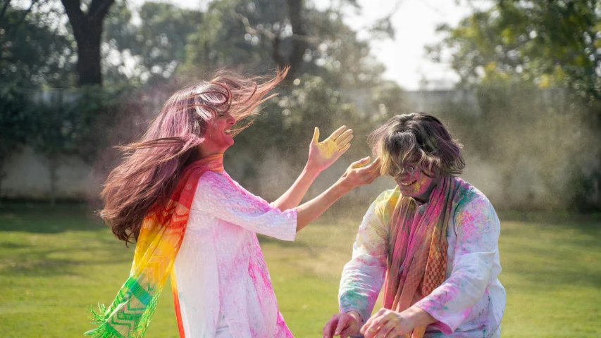 a couple of women standing on top of a lush green field, pexels contest winner, action painting, holi festival of rich color, hair blowing the wind, islamic, couple dancing