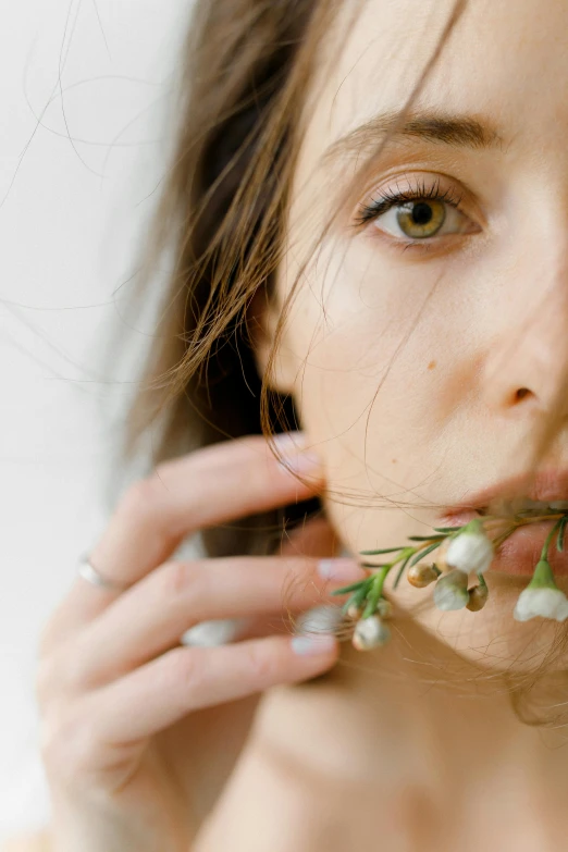 a woman with a flower in her mouth, inspired by Elsa Bleda, trending on unsplash, renaissance, with a white background, branches sprouting from her head, high angle closeup portrait, hand on her chin