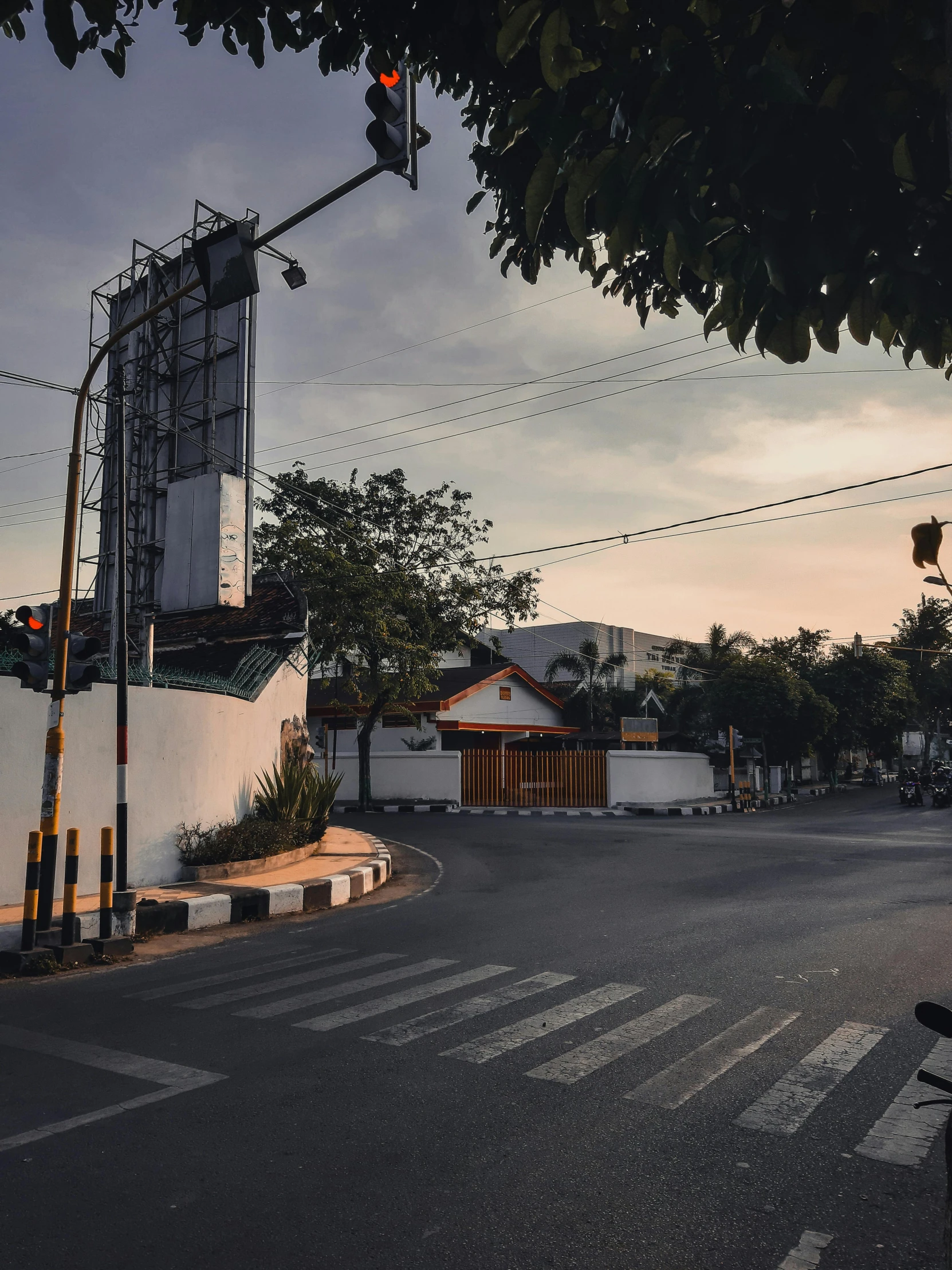 a man riding a motorcycle down a street next to a traffic light, a picture, pexels contest winner, sunset panorama, indonesia, background image, walking through a suburb