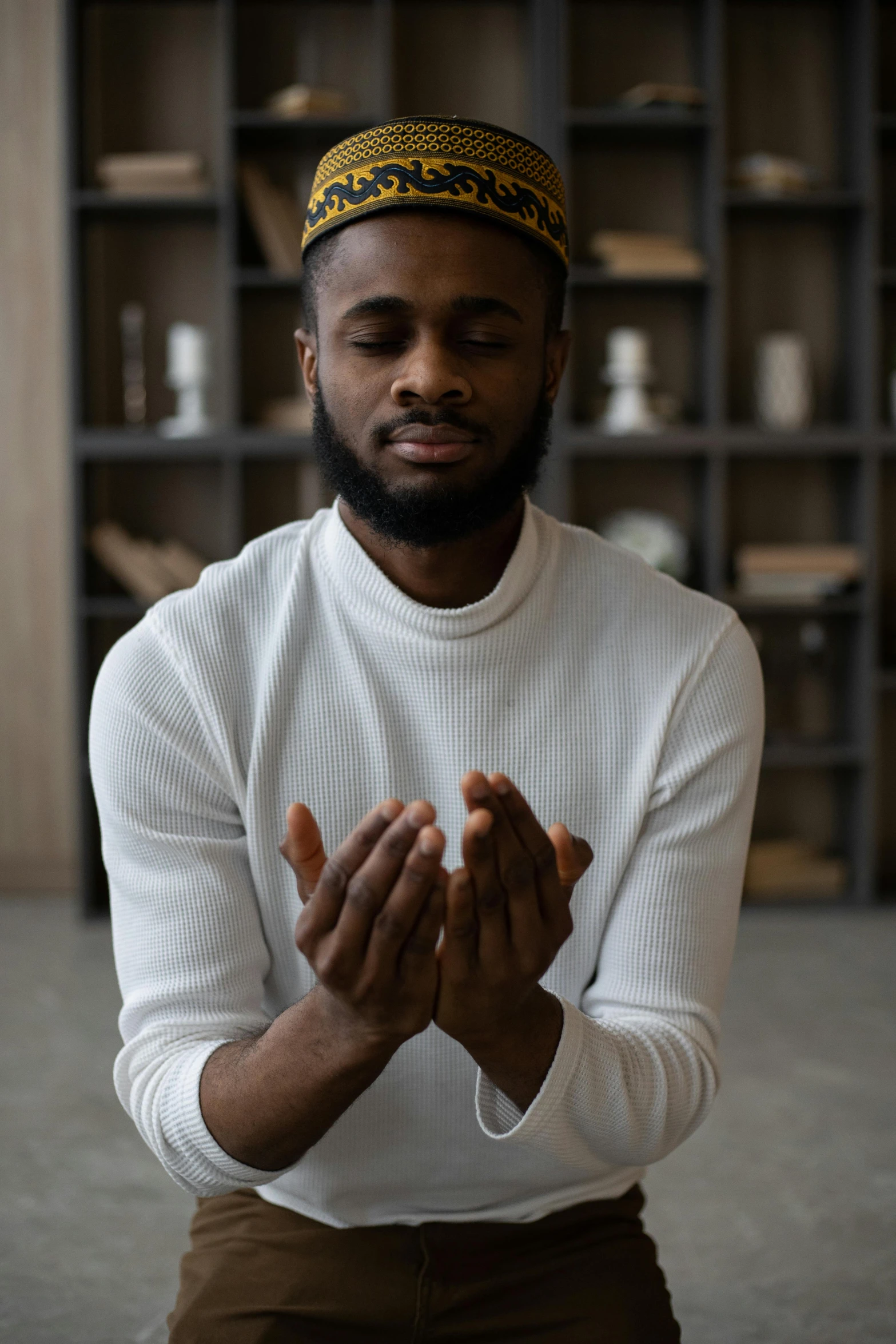 a man in a white shirt is praying, inspired by Oluf Høst, pexels contest winner, hurufiyya, jaylen brown, sheikh, he is wearing a brown sweater, meditating