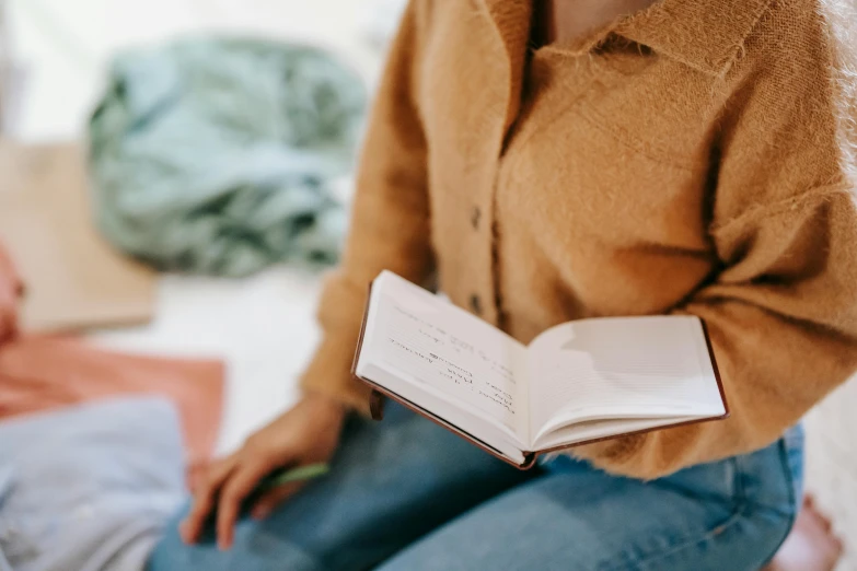 a woman sitting on a bed reading a book, trending on pexels, visual art, wearing a linen shirt, found written in a notebook, outfit photo, background image