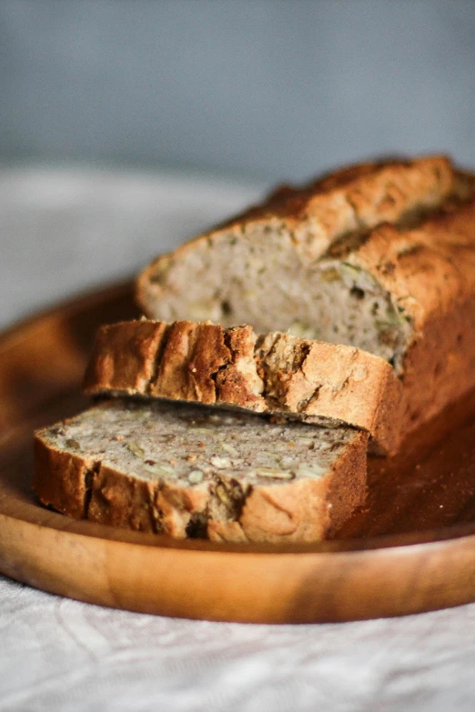 a loaf of bread sitting on top of a wooden plate, botanicals, cut, shot with sony alpha 1 camera, cake