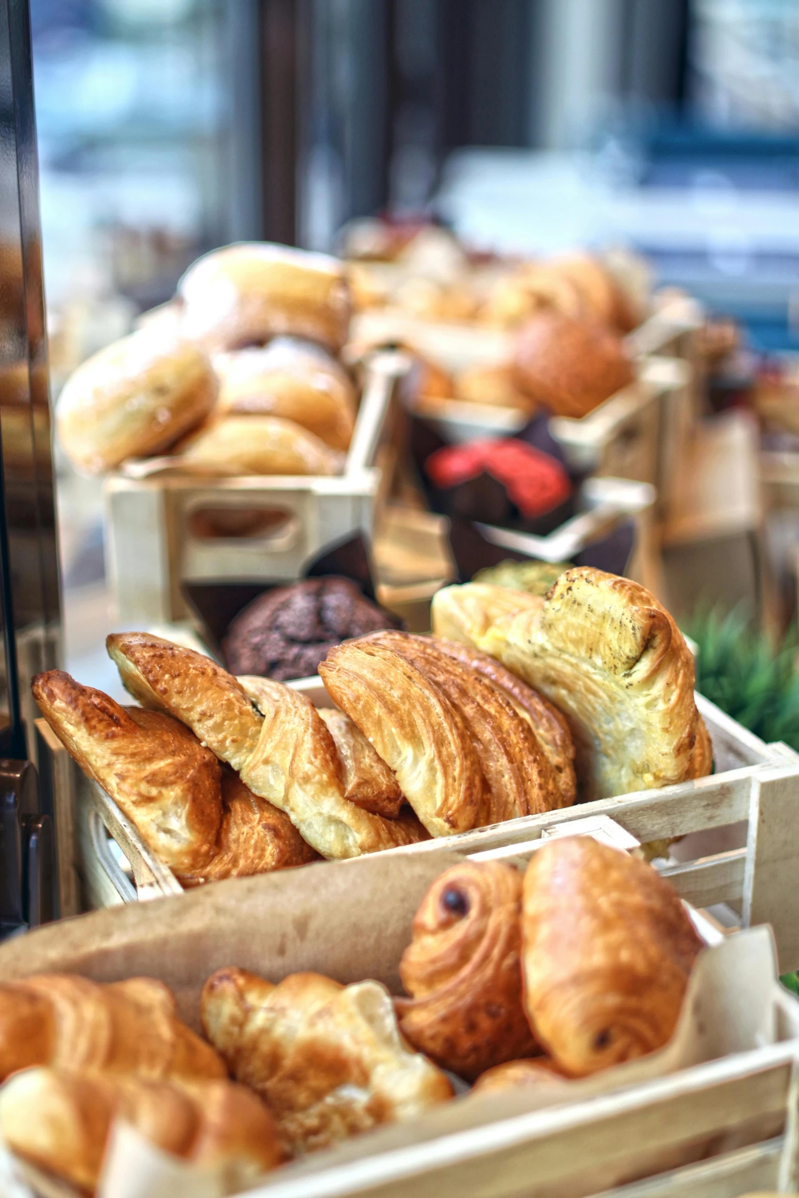 a display case filled with lots of different types of croissants, unsplash, square, warm sunlight shining in, a wooden