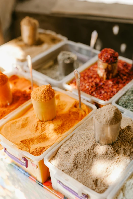 a table topped with lots of different types of spices, trending on unsplash, process art, jerusalem, intense sunlight, gray and orange colours, salsa vendor