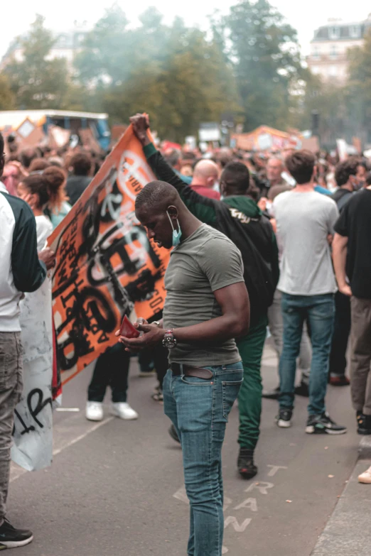 a large group of people walking down a street, a photo, by Jacob Toorenvliet, pexels, happening, wearing a bandana and chain, orange and black, placards, black man