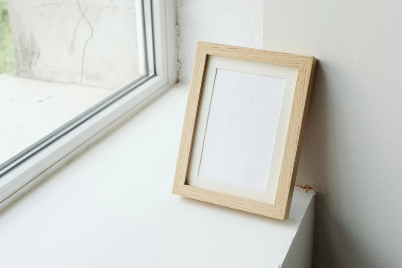 a picture frame sitting on a window sill next to a window, a picture, by Adam Rex, light wood, ecommerce photograph, studio photograph, portrait of a small