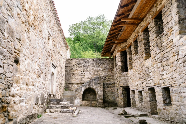 a stone building with a bench in the middle of it, pexels contest winner, romanesque, iron smelting pits, white wall complex, georgic, thumbnail