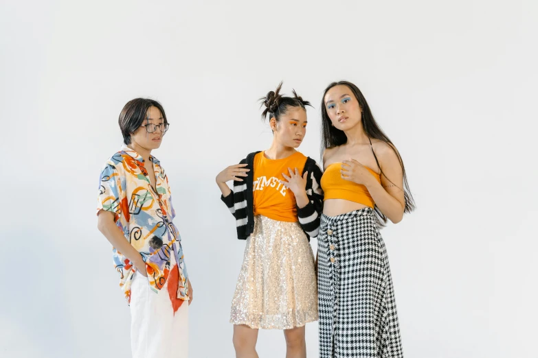 a group of three women standing next to each other, trending on pexels, white and orange, jpop clothing, studio shot, calarts