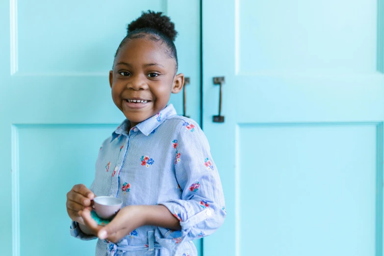 a little girl standing in front of a blue door, by Arabella Rankin, pexels contest winner, silver egg cup, light skinned african young girl, serving happy meals, beautiful wallpaper