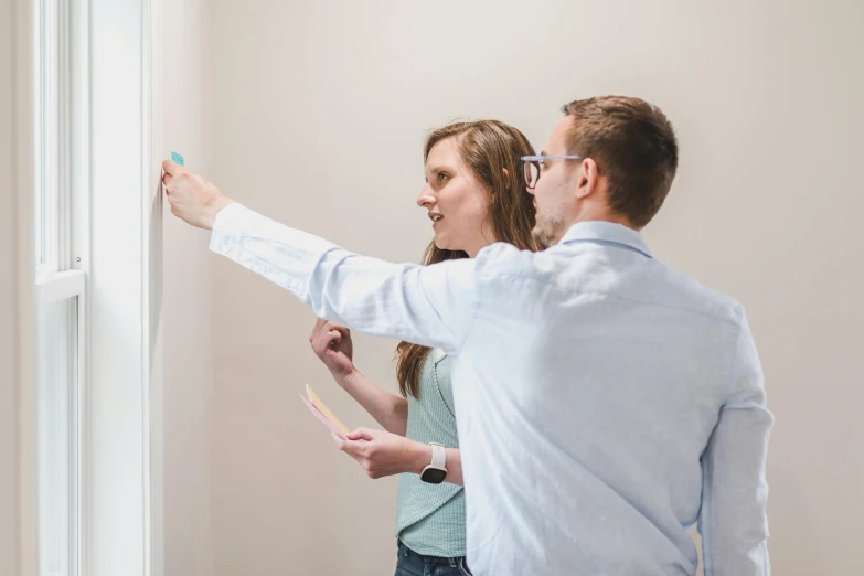 a man and a woman looking out a window, interactive art, whiteboard, white wall, holding a paintbrush, profile image