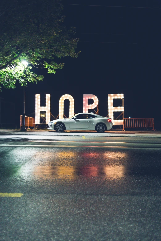 a car is parked in front of a hope sign, inspired by Carl Hoppe, unsplash contest winner, happening, lights on, profile image