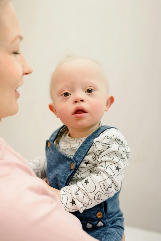 a woman holding a baby in her arms, by Arabella Rankin, pexels contest winner, albino dwarf, with a stethoscope, looking to his side, looking at each other mindlessly